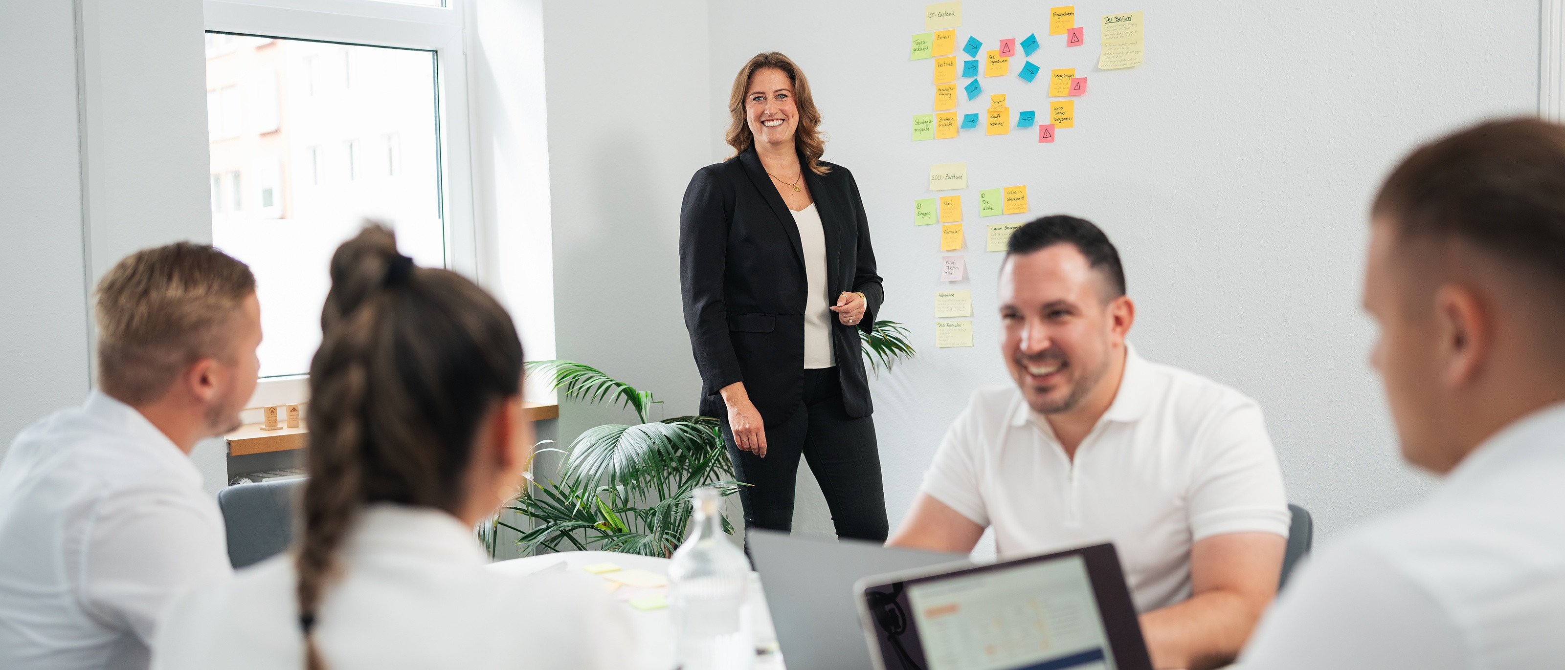 Workshop vor Ort, Fabienne Hermann vor der Prozesswand, das Team am Tisch