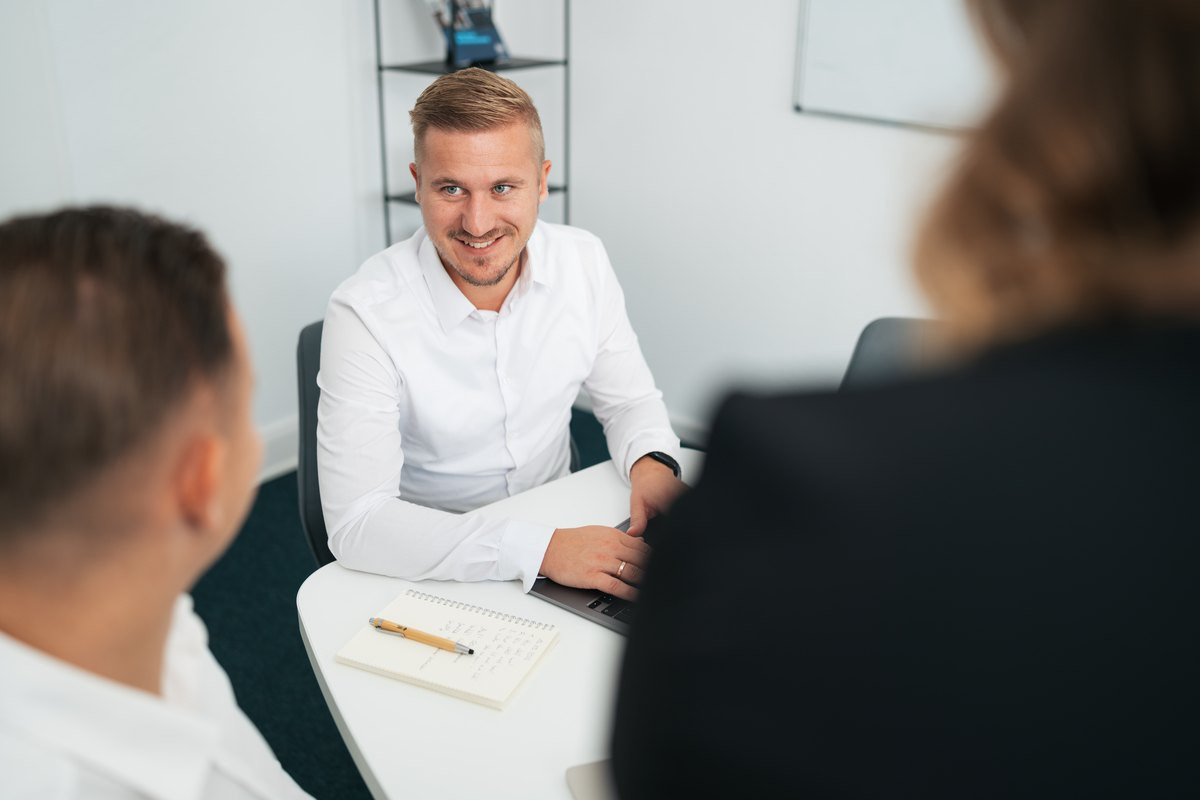 Gespräch am Besprechungstisch, ein Teilnehmer hört zu