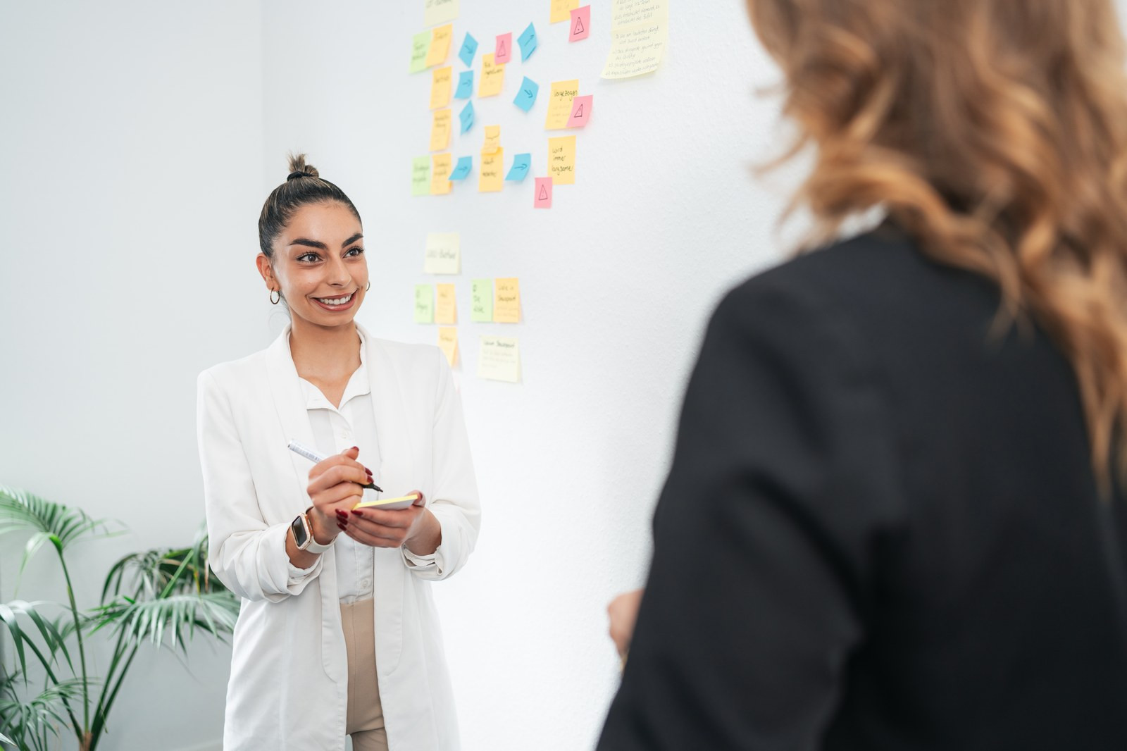 Gespräch vor einer Wand mit Haftnotizen aus einem Workshop
