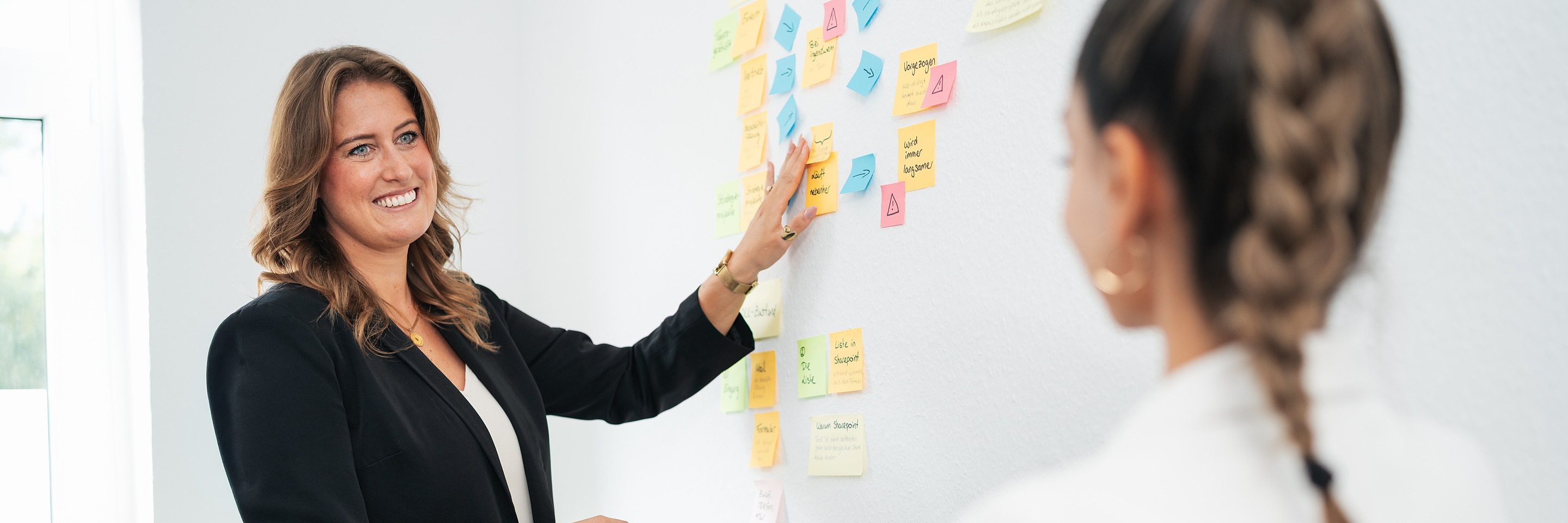 Fabienne Hermann erklärt an einer Wand mit Haftnotizen